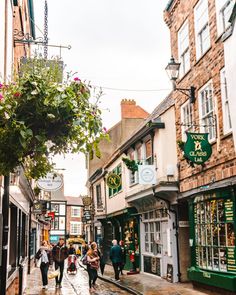 people are walking down the street in an old european town with shops and stores on both sides