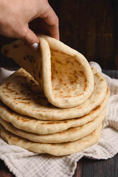 a stack of pita bread on top of a white cloth next to a wooden table