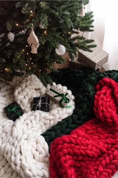 a christmas tree with presents under it and a blanket on the floor next to it