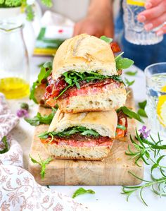 two sandwiches stacked on top of each other with herbs and lemons in the background