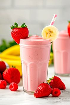 two smoothies with bananas and strawberries on the table next to some other fruit