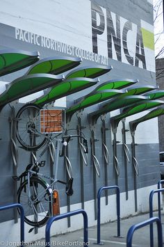 several green and white umbrellas are attached to the side of a building with bicycles parked underneath them