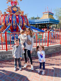 a woman and two children standing in front of a carnival ride