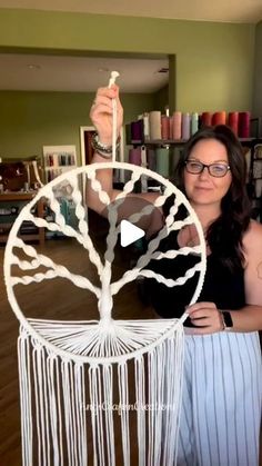 a woman holding up a white dream catcher