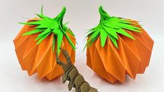 two origami pumpkins sitting on top of each other with green leaves attached to them