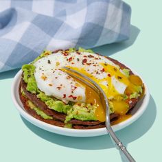 an open faced sandwich with avocado and poached eggs on it, sitting on a plate