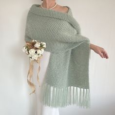 a woman wearing a green knitted shawl with fringes and flowers on it