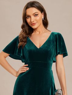 a woman wearing a green velvet dress with short sleeves and an asymmetrical neckline