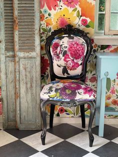 a chair with flowers painted on it sitting in front of a wallpapered room