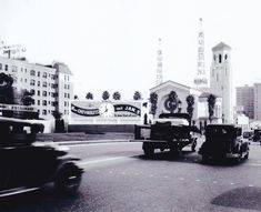 an old black and white photo of cars driving down the street