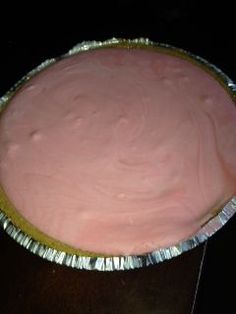 a pink cake in a tin foil container on a black counter top with gold trim