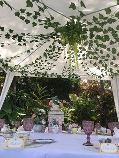 the table is set for an outdoor tea party with white linens and greenery