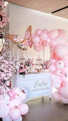 pink balloons and flowers are on display at the entrance to a wedding reception with a butterfly theme