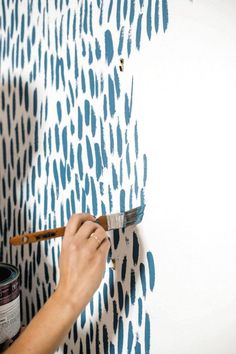 a person using a paintbrush to paint a wall with blue and white designs on it