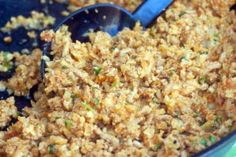 a close up of food in a bowl with a spoon on the side and green onions sprinkled over it