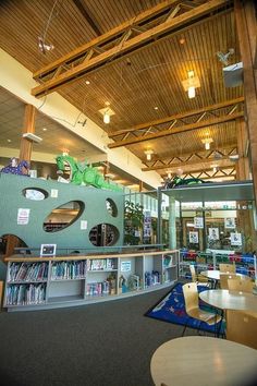 the inside of a library with tables, chairs and bookshelves filled with children's books