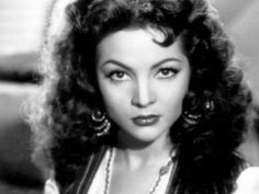 an old black and white photo of a woman with long curly hair wearing large earrings