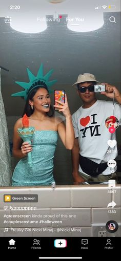 two people standing in front of a mirror holding up cell phones and taking selfies