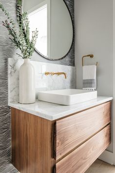 a white sink sitting on top of a wooden cabinet next to a wall mounted mirror