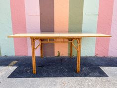 a wooden table sitting in front of a wall with multicolored stripes on it