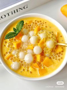 a white bowl filled with fruit and ice cream next to an orange slice on top of a book