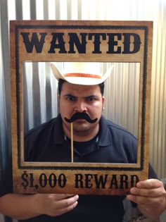 a man with a fake mustache holding up a wanted sign