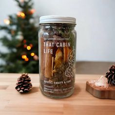 a glass jar filled with cinnamons and spices next to a pine cone on a table