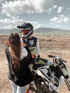 two people standing next to each other on a dirt bike in the middle of nowhere