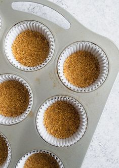 a muffin tin filled with brown crumbs on top of a white counter