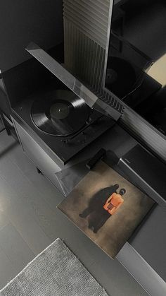 a record player sitting on top of a table next to a rug with a painting