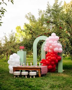 an outdoor party setup with balloons and picnic table in the middle of apple orchards