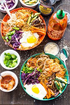 two bowls filled with different types of food on top of a wooden table next to condiments