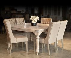 a wooden table with chairs around it and a vase filled with white flowers on top