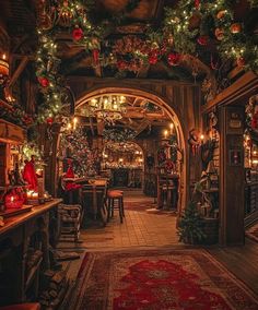 an archway decorated for christmas with lights and decorations hanging from it's ceiling, surrounded by greenery