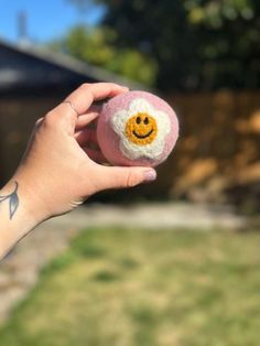 a hand holding a small smiley face ball