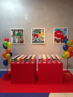 there are two red boxes on the floor with balloons in front of them and pictures hanging on the wall behind them