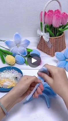 a person cutting paper flowers with scissors on a table next to other crafting supplies