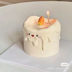 a white cake with icing on it and a lit candle in the middle that is shaped like an elephant