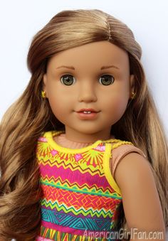 a close up of a doll with long hair wearing a colorful dress and gold earrings