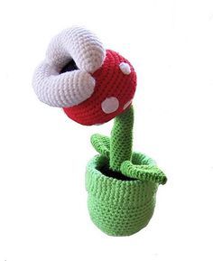 a crocheted stuffed mushroom sitting in a green pot with a white polka dot on it