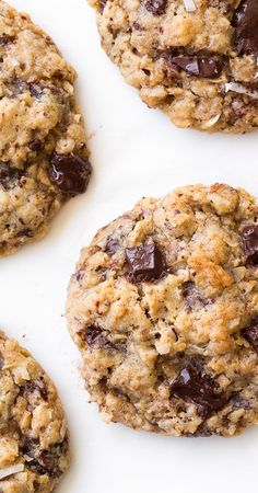 four chocolate chip cookies on a white surface