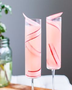 two glasses filled with pink liquid sitting on top of a table next to each other