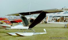 an airplane sitting on top of a lush green field next to other small planes in the background