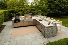 an outdoor kitchen with stainless steel appliances and seating