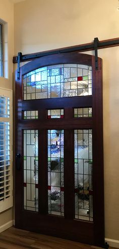 a large wooden door with stained glass panels on the top and bottom panel, in front of a window