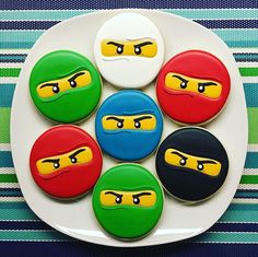 four decorated cookies on a white plate with ninja turtles in the middle one is yellow, green and blue