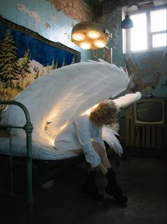 a woman sitting on top of a bed covered in white wings