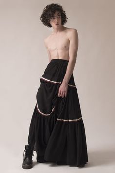 a shirtless man in a long black skirt