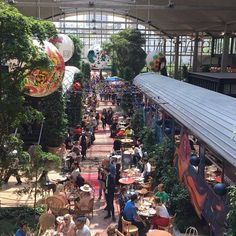 an indoor restaurant with lots of tables and people sitting at it's tables in the middle