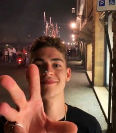 a young man making the vulcan sign with his hand on a city street at night